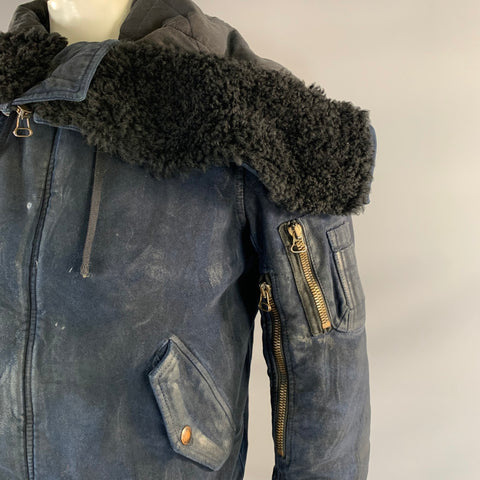 Close-up of the jacket shoulder, black shearling-style panel, front zipper, flap pocket, and gold-tone sleeve zipper.