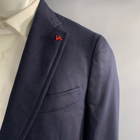 Close-up of navy textured wool sport coat notch lapel with red Isaia lapel pin.