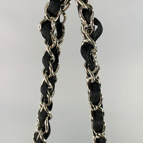 Close-up of black fabric threaded through silver-tone chain shoulder straps.