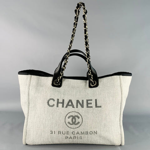 Front view of grey woven Chanel tote with black leather handles and black-woven silver-tone chain shoulder straps.