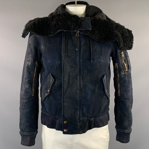 Front view of navy Balmain bomber jacket with black shearling-style shoulder panel, zip front, snap hem, flap pockets, and sleeve zip pockets.