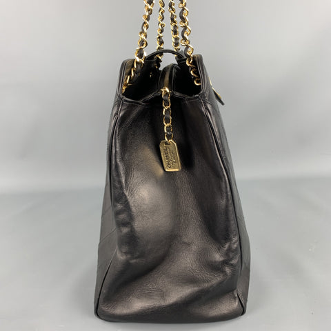 Side view of black leather handbag showing gold-tone Chanel Paris hangtag and side zipper detail.