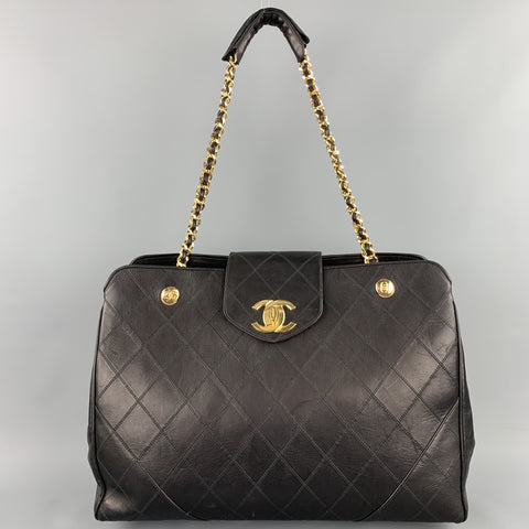 Front view of black quilted Chanel handbag with chain shoulder straps raised.