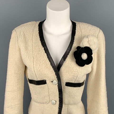 Close front view showing the V-neck black leather trim, black camellia applique, button closure, and pocket trim.