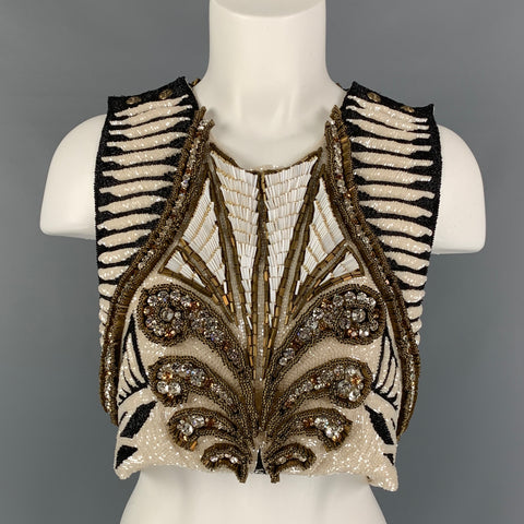 Front view of white, black, and gold sleeveless cropped silk top on a mannequin with dense beadwork, crystals, and striped shoulders.
