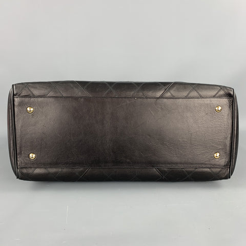 Bottom view of black leather handbag with four gold-tone protective feet.