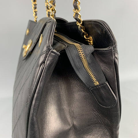 Angled close-up of handbag top opening, chain attachment, and gold-tone zipper.
