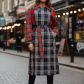 Woman wearing a plaid dress on a street with shops in the background