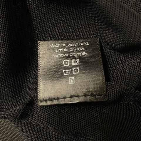 Close-up of care label stating machine wash cold, tumble dry low, and remove promptly.