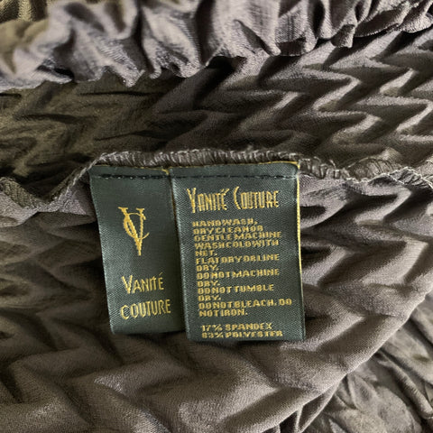 Close-up of VANITE COUTURE label and care label on pleated fabric.
