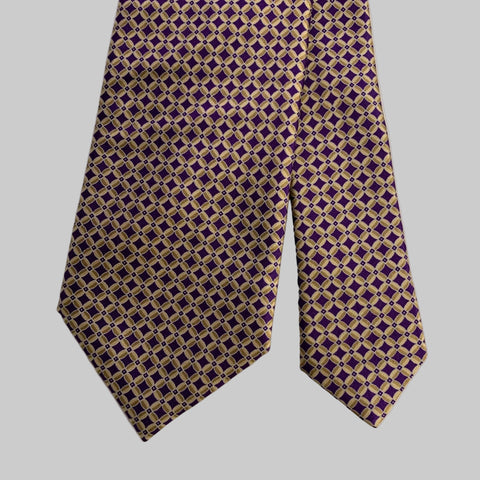 Purple and gold patterned tie on a gray background
