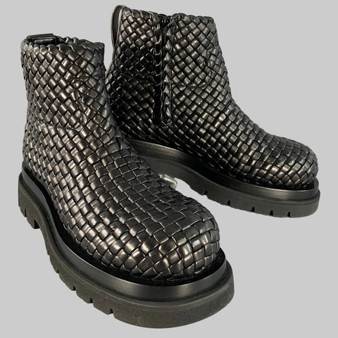 A pair of black BOTTEGA VENETA woven leather boots with side zipper and lug sole.