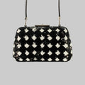 Black handbag with silver floral patterns on a gray background