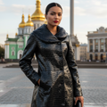 Black leather embossed coat with rabbit fur lining, featuring a large collar, double breasted closure, and slit pockets, displayed on a mannequin.