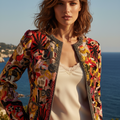 OSCAR DE LA RENTA jacket on a mannequin displaying a vibrant abstract pattern with yellow and red colors, adorned with beaded trim and colorful ribbon details.