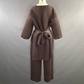 Back view of brown chevron-pleated top with tied belt at waist and matching pants.