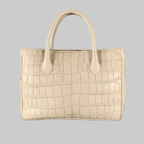A grey crocodile leather tote handbag with rolled top handles and a snap closure. The handbag appears to be made of a textured leather with a natural grey crocodile pattern.