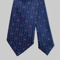 Navy blue tie with pink geometric pattern on a light gray background