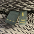 Close-up of VANITE COUTURE garment labels on chevron-pleated fabric.