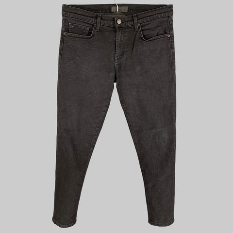 A pair of J.BRAND black cotton slim fit jeans with a zip fly closure, displayed against a plain background.