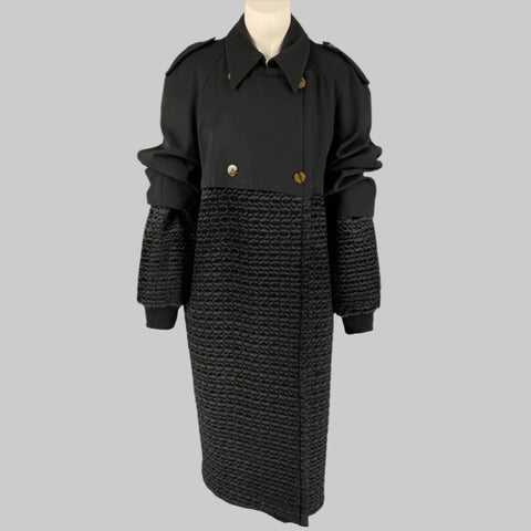 Vintage 1980's black quilted double-breasted trench coat with a pointed collar, ribbed hem, and slit pockets on a mannequin.